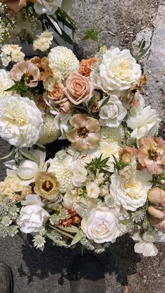 a bunch of flowers sitting on the ground next to each other in front of a person's feet