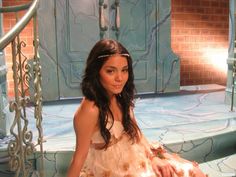 a woman in a dress sitting on the steps with her hand on her hip and looking at the camera