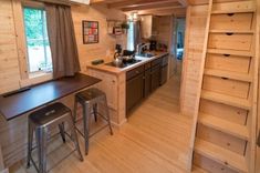 a kitchen and dining area in a tiny cabin with stairs leading up to the loft