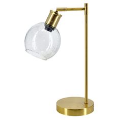 a gold table lamp with a clear glass ball on the base and a brass metal arm