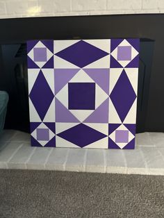 a purple and white painting sitting on top of a fireplace