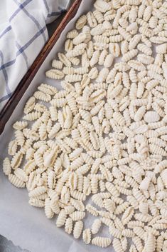 some kind of pasta that is on top of a sheet of paper and next to a wooden spoon