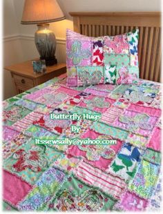 a bed with colorful quilts and pillows on top of it next to a lamp