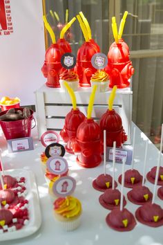 a table topped with lots of red and yellow cupcakes