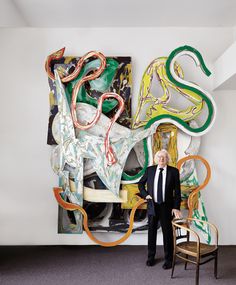 a man standing next to a chair in front of a painting