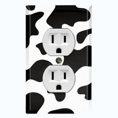 a black and white cow print outlet cover with two outlets in the middle, on an off - white background