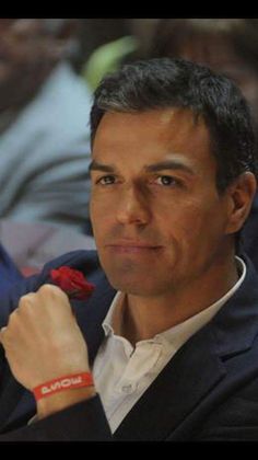 a man with a watch on his wrist in front of other people at a conference