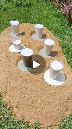 there are many cups in the sand on the ground and one cup has been placed at the base