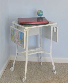 a small white desk with a globe on top and a laptop computer sitting on it