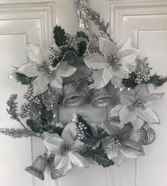 a wreath with silver and white flowers on the front door, decorated with greenery