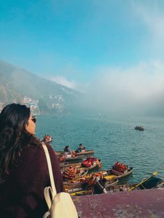 a woman is looking out over the water at boats in the harbor on a foggy day