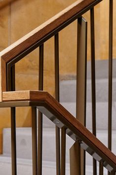 a cat sitting on top of a wooden banister next to a hand rail and stairs