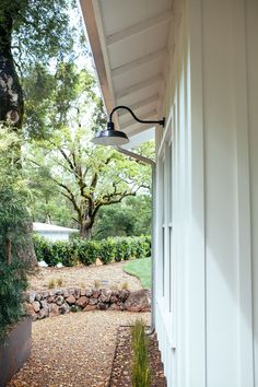 an outside view of a white house with trees and bushes