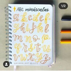 an open notebook with writing on it next to some markers and pencils in front of it