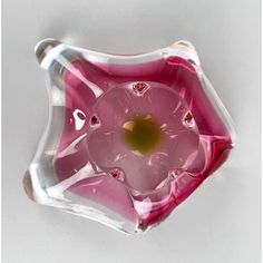 a pink flower shaped glass dish on a white surface