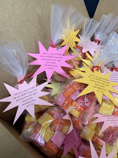 a box filled with lots of candy wrapped in cellophane and some pink and yellow stars