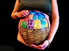 a pregnant woman is holding her belly painted like an easter basket