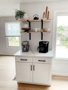 a kitchen with white cupboards and shelves filled with coffee cups on top of them