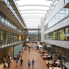 people are walking through an indoor mall with lots of glass and metal balconies