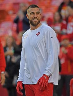 a man in red and white uniform standing on the sidelines with his hands behind his back