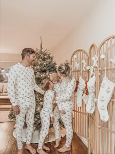 a family in pajamas standing next to a christmas tree