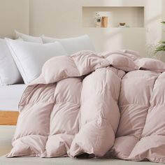 an unmade bed with pink comforter and pillows