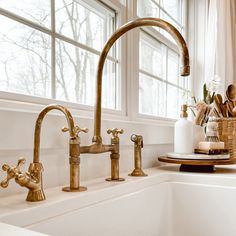 a kitchen sink with brass faucets and soap dispenser next to it