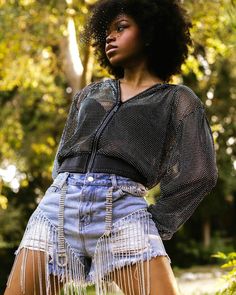 a woman standing in the grass with her hands on her hips and wearing high waisted shorts