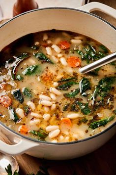 a pot filled with soup and vegetables on top of a wooden table