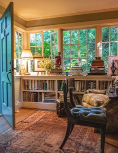 a living room filled with furniture and bookshelves next to a window covered in lots of windows