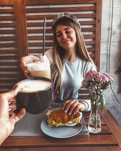 a woman sitting at a table with a plate of food in front of her and a cup of coffee