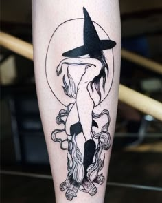 a black and white photo of a woman with a witches hat on her leg,