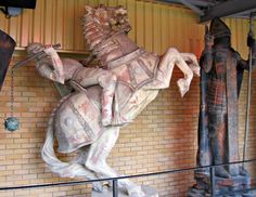 a statue of a man riding on the back of a horse in front of a brick wall