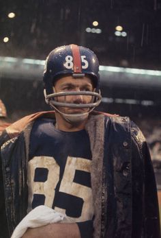 an old football player holding a baby in his arms and wearing a helmet with the number 35 on it