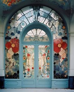 an ornate blue door with stained glass and flowers on it's front entrance to a building