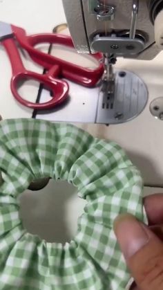 someone is using scissors to sew the fabric on a green and white checkered scrunch