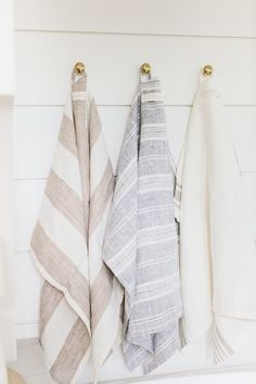 three towels are hanging on the wall next to each other in a room with white walls