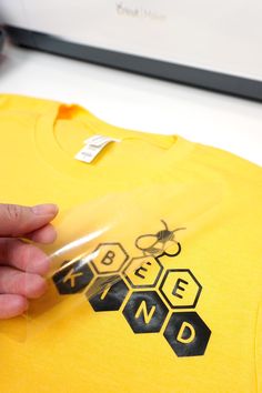 a person holding onto a yellow t - shirt with bees on it