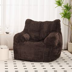 a brown chair sitting on top of a white floor next to a potted plant