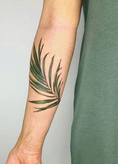 a person with a tattoo on their arm that has a palm tree leaf on it