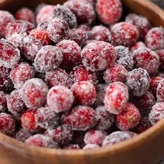 a wooden bowl filled with sugar covered cranberries