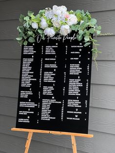 a black and white wedding seating chart on a wooden easel with flowers in it