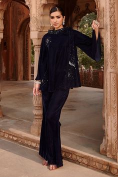 Navy blue velvet top with celestial scattered embroidery. Comes with flared pant.
Component: 2
Pattern: Embroidered
Type Of Work: Celestial
Neckline: Band collar
Sleeve Type: Full
Fabric: Velvet
Color: Blue
Other Details: 
Knot detailing
Note : Outfit worn by the model on the left is not for sale.
Occasion: Work - Aza Fashions Blue Velvet Top, Velvet Top, Velvet Color, Velvet Pants, Fashion App, Collar Top, Band Collar, Velvet Tops, Blue Pants