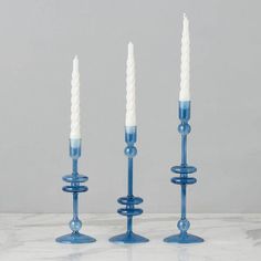 three blue candle holders with white candles in them