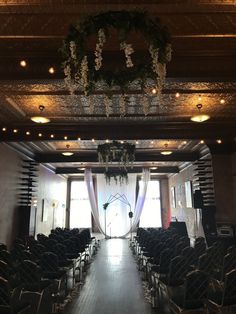 an empty hall with rows of chairs and chandeliers hanging from the ceiling, decorated for a wedding ceremony