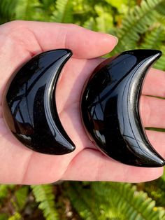 two black glass crescents are held in someone's hand