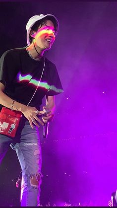 a man standing on top of a stage wearing headphones and holding a red bag