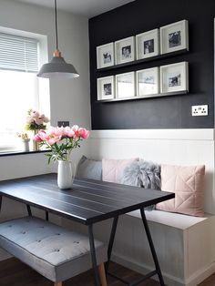 a table with flowers in a vase on top of it next to a bench and window