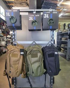 several backpacks are sitting on a rack in a store with other items behind them