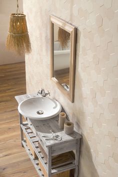 a white sink sitting under a mirror next to a wooden shelf